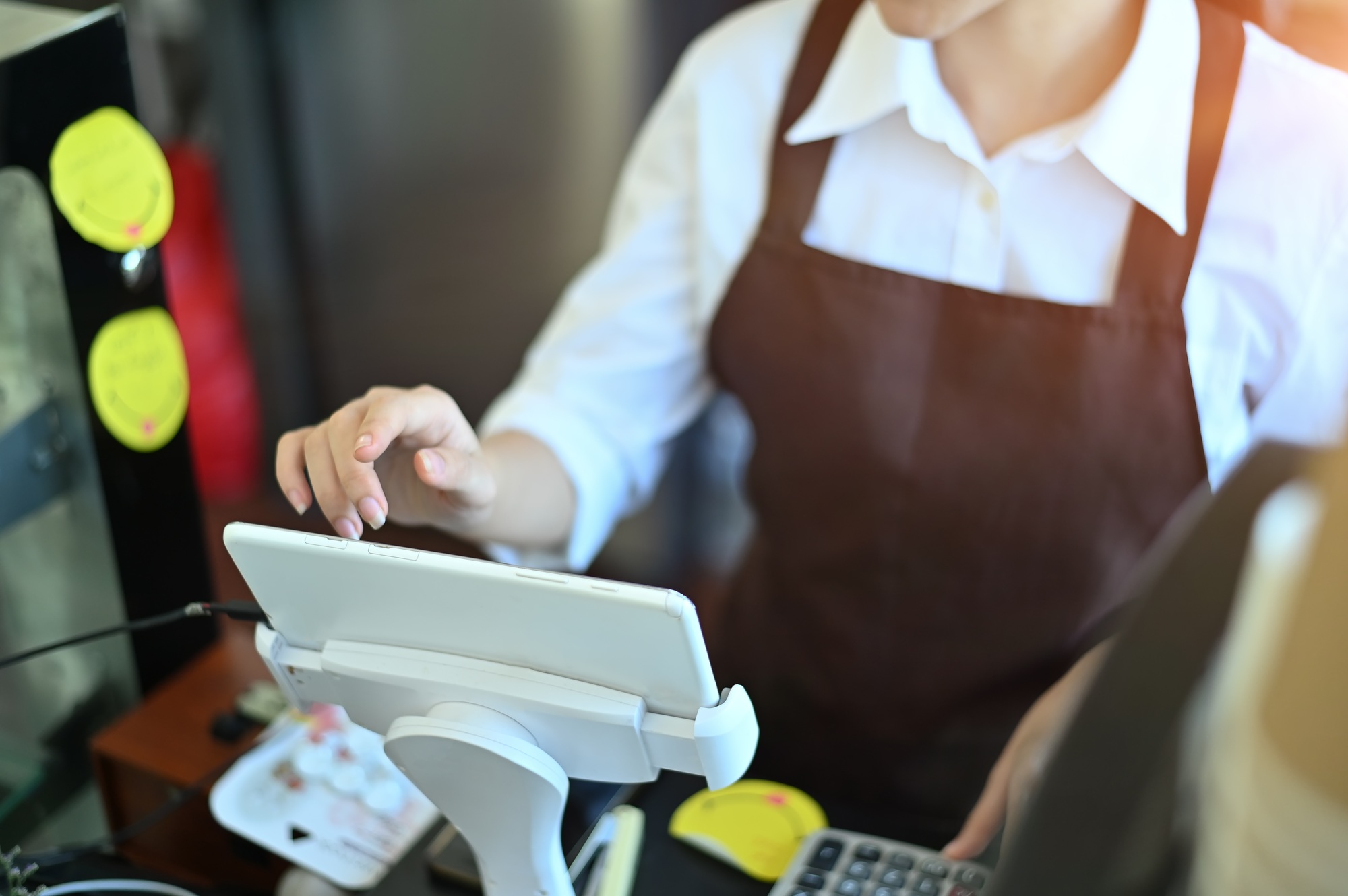 Cropped shot barista using mobile ordering Kitchen System with digital tablet.