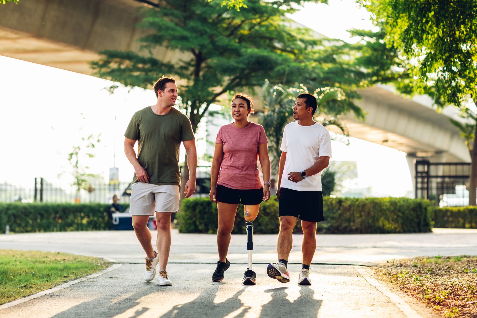 Friend support Friend with a prosthetic leg while exercising outdoor.
