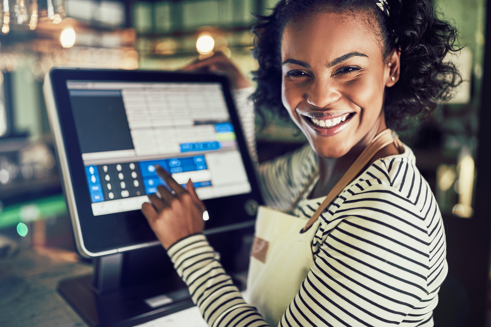 Smiling young waitress using a restaurant point of sale terminal